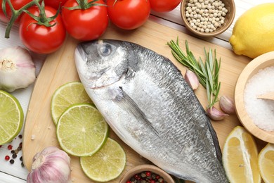 Photo of Fresh raw dourade with spices on white wooden table, flat lay. Fish and seafood delicacies