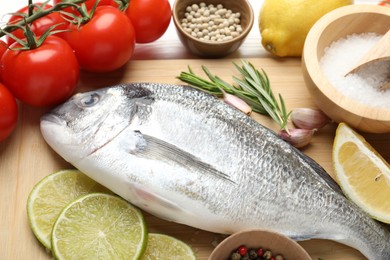 Photo of Fresh raw dourade with spices on white wooden table, closeup. Fish and seafood delicacies