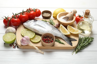 Photo of Fresh raw dourade with spices on white wooden table. Fish and seafood delicacies