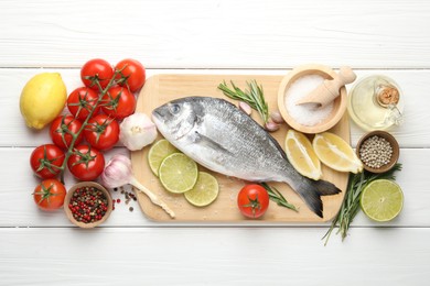 Photo of Fresh raw dourade with spices on white wooden table, flat lay. Fish and seafood delicacies