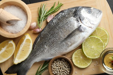 Photo of Fresh raw dourade with spices on table, closeup. Fish and seafood delicacies
