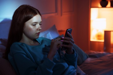 Photo of Beautiful teenage girl using smartphone on bed at home