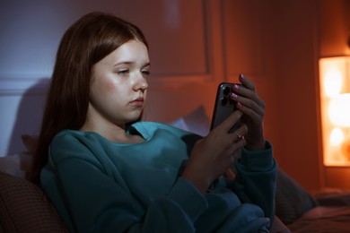 Photo of Beautiful teenage girl using smartphone on bed at home