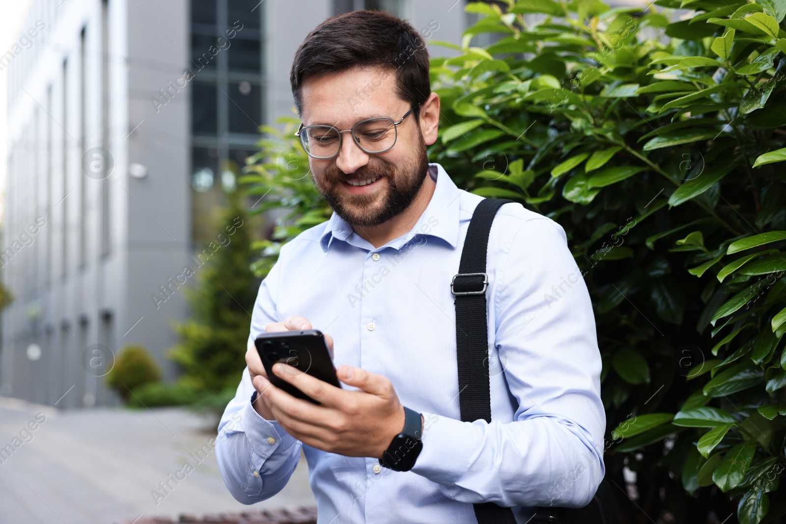 Successful businessman with smartphone near office building Photo of Successful businessman with smartphone near office building
