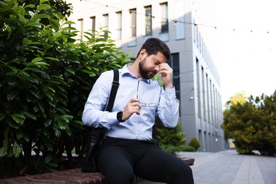 Photo of Tired businessman with glasses outside office building