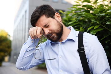 Photo of Tired businessman with glasses outside office building