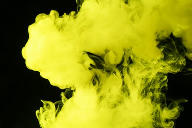 Photo of Hookah smoke in yellow light on black background, closeup
