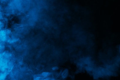 Photo of Hookah smoke in blue light on black background, closeup