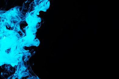 Photo of Hookah smoke in blue light on black background, closeup. Space for text