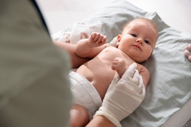 Photo of Pediatrician examining baby at table in clinic, closeup