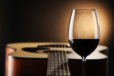 Photo of Acoustic guitar and glass of red wine on black background, closeup. Space for text