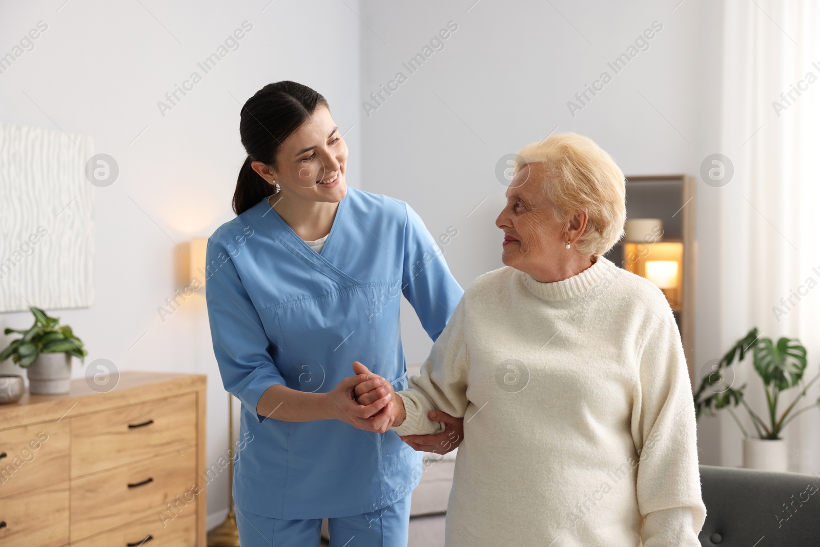 Nurse assisting senior woman indoors. Home health care service Photo of Nurse assisting senior woman indoors. Home health care service