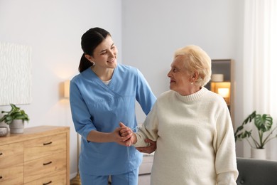 Photo of Nurse assisting senior woman indoors. Home health care service