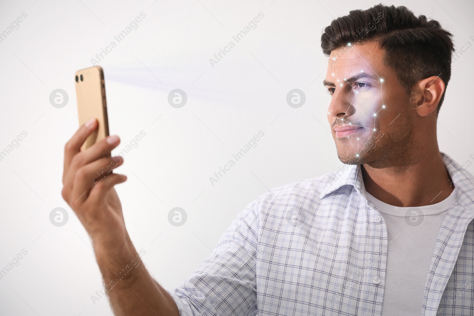 Man unlocking his smartphone with facial scanner against light background. Biometric verification Image of Man unlocking his smartphone with facial scanner against light background. Biometric verification