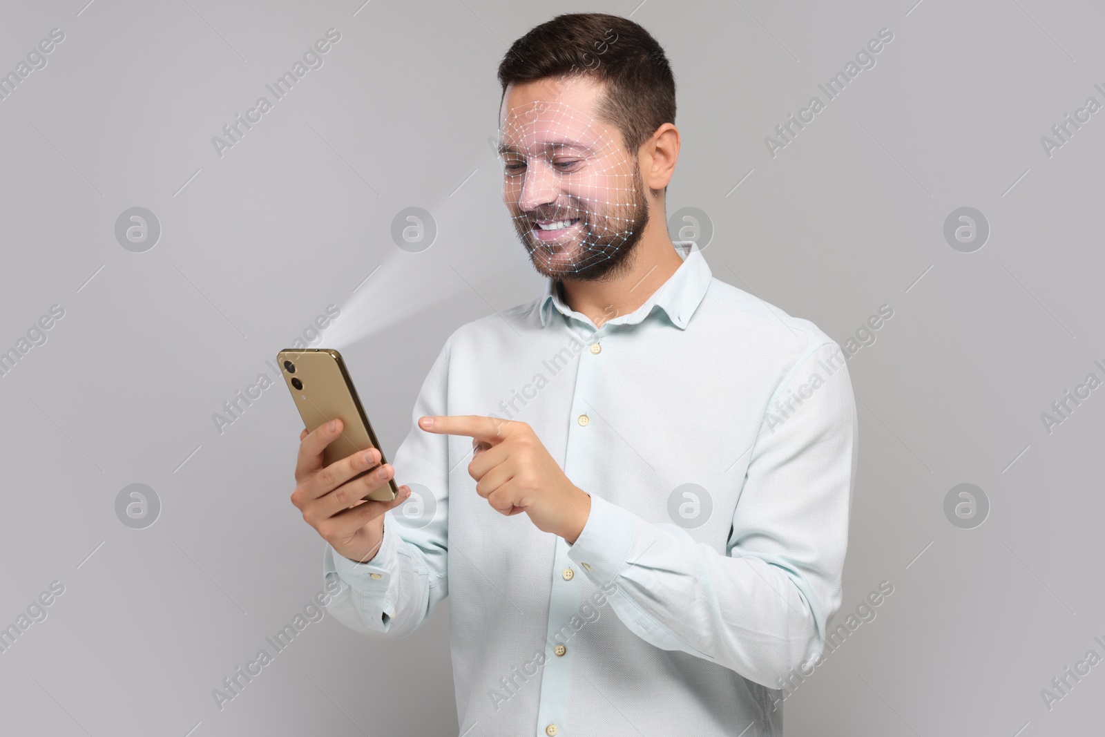 Man unlocking his smartphone with facial recognition app against light grey background. Biometric verification Image of Man unlocking his smartphone with facial recognition app against light grey background. Biometric verification