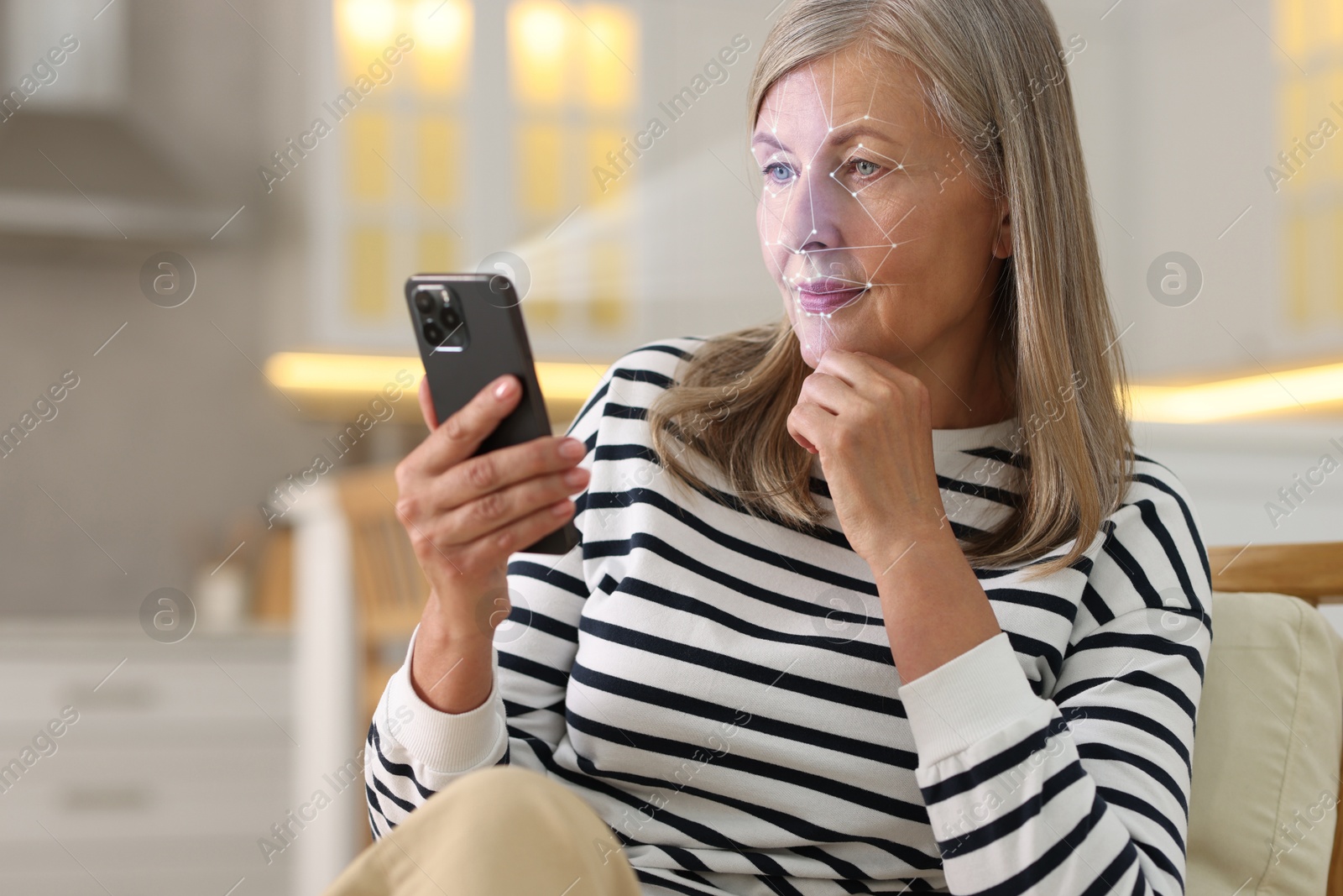 Woman unlocking her smartphone with facial scanner in kitchen. Biometric verification Image of Woman unlocking her smartphone with facial scanner in kitchen. Biometric verification