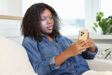 Image of Woman unlocking her smartphone with facial recognition app at home. Biometric verification