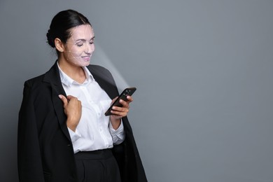 Image of Woman unlocking her smartphone with facial scanner against grey background. Biometric verification