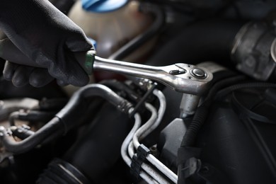 Photo of Auto parts. Professional mechanic with torque wrench fixing car indoors, closeup