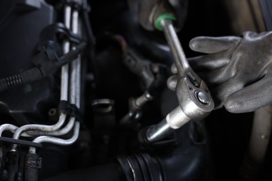 Photo of Auto parts. Professional mechanic with torque wrench fixing car indoors, closeup