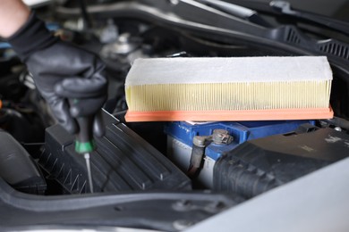 Photo of Auto part. Professional mechanic with screwdriver fixing car indoors, focus on air filter