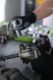 Photo of Auto parts. Professional mechanic fixing manual transmission at grey table indoors, closeup