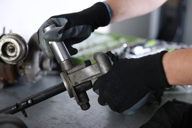 Photo of Auto parts. Professional mechanic fixing manual transmission at grey table indoors, closeup