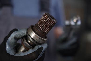 Photo of Auto part. Professional mechanic with drive shaft and tool indoors, closeup. Space for text