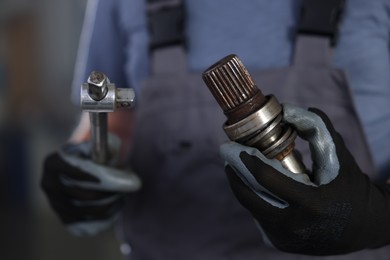 Photo of Auto part. Professional mechanic with drive shaft and tool indoors, closeup