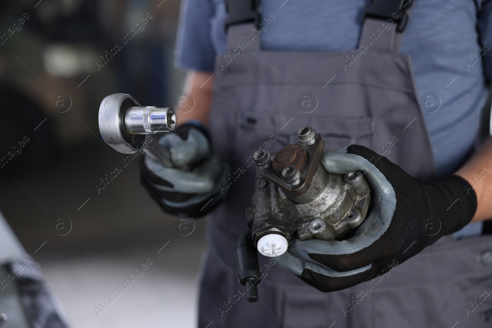 Auto part. Professional mechanic with hydraulic pump and socket wrench indoors, closeup Photo of Auto part. Professional mechanic with hydraulic pump and socket wrench indoors, closeup