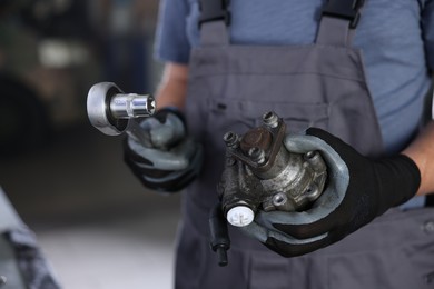 Photo of Auto part. Professional mechanic with hydraulic pump and socket wrench indoors, closeup