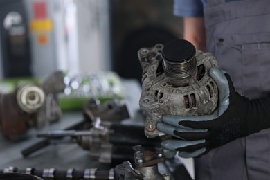 Photo of Auto parts. Professional mechanic with alternator near indoors, closeup. Space for text