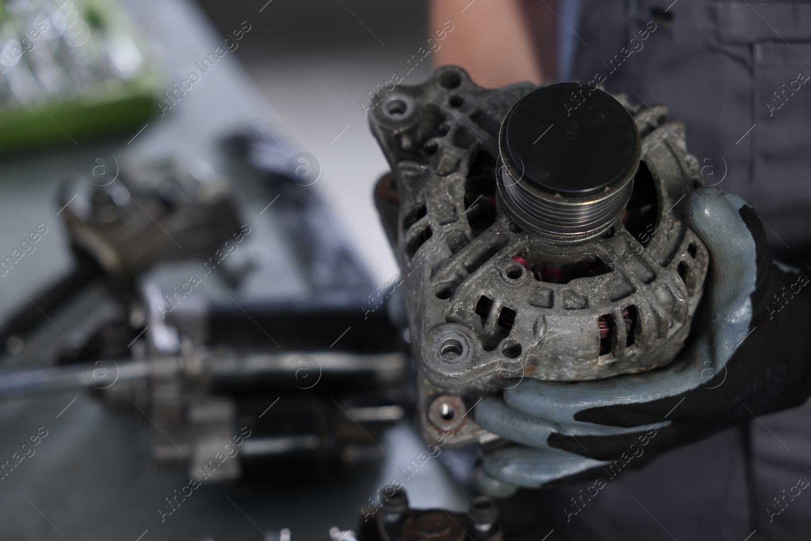 Auto parts. Professional mechanic with alternator near indoors, closeup. Space for text Photo of Auto parts. Professional mechanic with alternator near indoors, closeup. Space for text