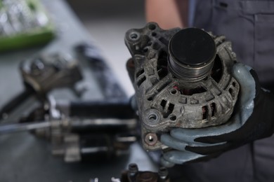 Photo of Auto parts. Professional mechanic with alternator near indoors, closeup. Space for text