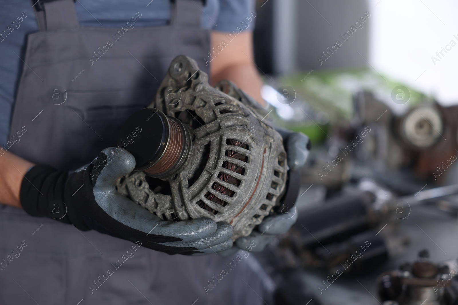 Auto parts. Professional mechanic with alternator near indoors, closeup. Space for text Photo of Auto parts. Professional mechanic with alternator near indoors, closeup. Space for text