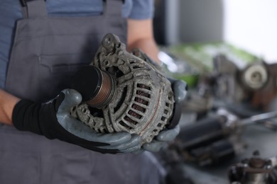 Photo of Auto parts. Professional mechanic with alternator near indoors, closeup. Space for text