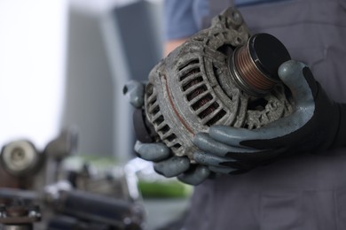 Photo of Auto parts. Professional mechanic with alternator near indoors, closeup. Space for text