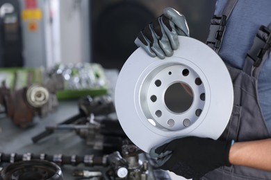 Photo of Auto parts. Professional mechanic with brake disc indoors, closeup