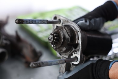 Photo of Auto part. Professional mechanic with starter motor indoors, closeup
