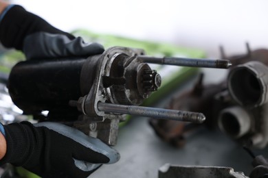 Photo of Auto part. Professional mechanic with starter motor indoors, closeup