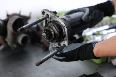 Photo of Auto part. Professional mechanic with starter motor indoors, closeup