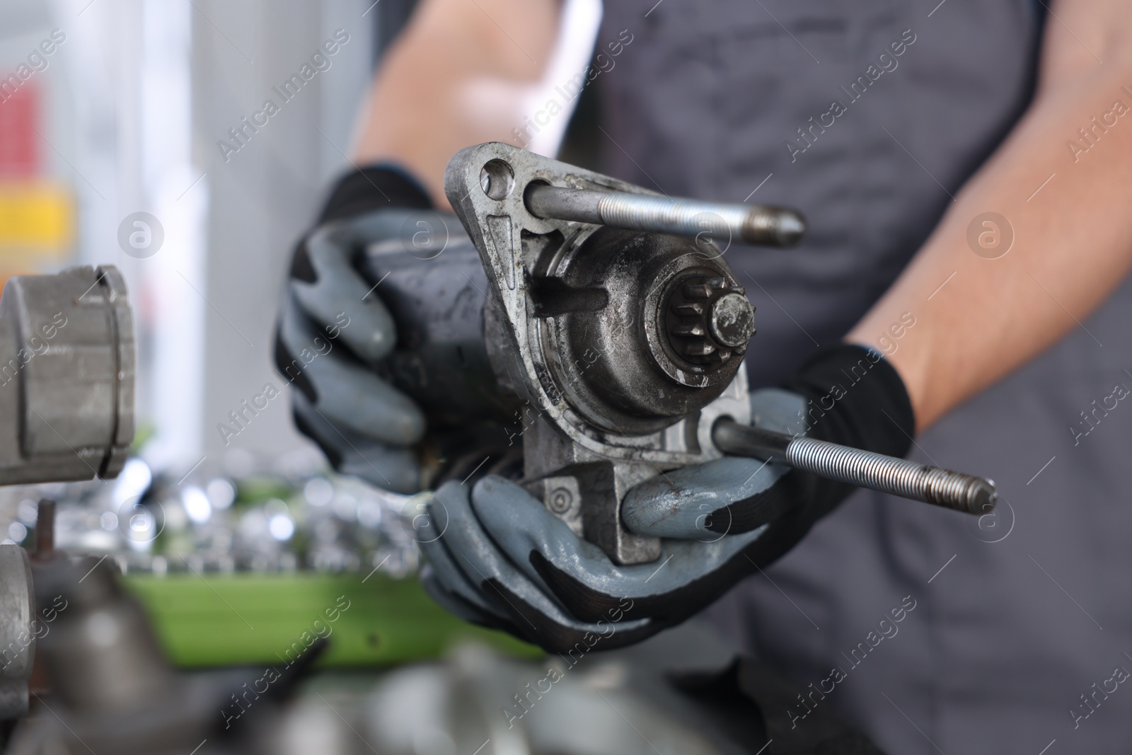 Auto part. Professional mechanic with starter motor indoors, closeup Photo of Auto part. Professional mechanic with starter motor indoors, closeup