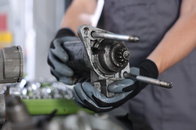 Photo of Auto part. Professional mechanic with starter motor indoors, closeup