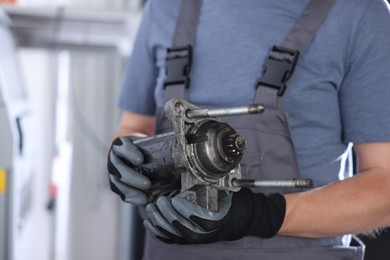 Photo of Auto part. Professional mechanic with starter motor indoors, closeup. Space for text