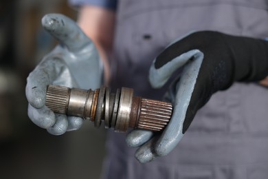 Photo of Auto part. Professional mechanic with drive shaft indoors, closeup