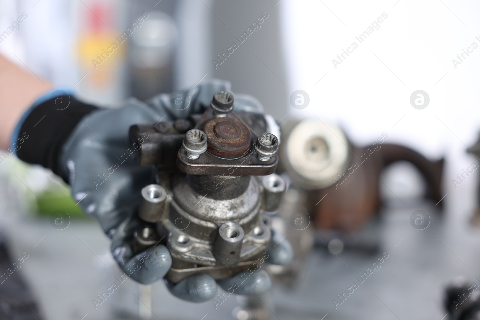 Auto part. Professional mechanic with power steering pump indoors, closeup. Space for text Photo of Auto part. Professional mechanic with power steering pump indoors, closeup. Space for text