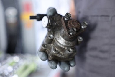 Photo of Auto part. Professional mechanic with power steering pump indoors, closeup. Space for text