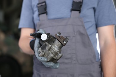 Photo of Auto part. Professional mechanic with power steering pump indoors, closeup
