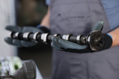 Photo of Auto part. Professional mechanic with camshaft indoors, closeup view