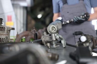 Photo of Professional mechanic with camshaft indoors, focus on different auto parts